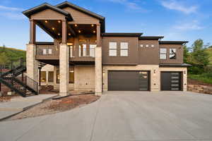 View of front facade featuring a garage, driveway, stairway, a standing seam roof, and a balcony