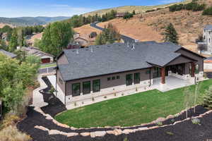 Back of property with a patio area, a shingled roof, a mountain view, and a lawn