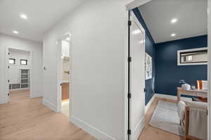 Hallway with light wood finished floors and recessed lighting