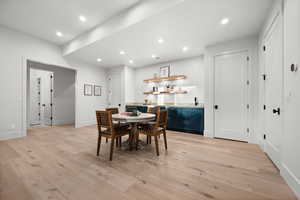 Dining room featuring bar with sink, light wood-style flooring, and recessed lighting