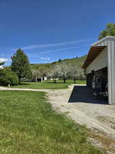 View of green lawn featuring a pole building, driveway, an outdoor structure, and a garage