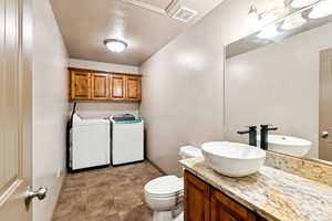 Bathroom featuring washing machine and dryer, vanity, and a textured ceiling