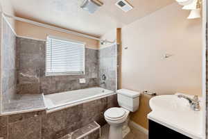 Bathroom with tiled shower / bath combo, vanity, tile patterned floors, and a textured ceiling