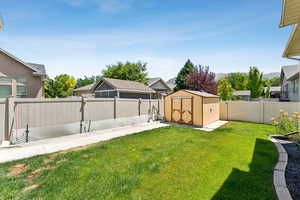 Fenced backyard featuring a storage shed and a residential view