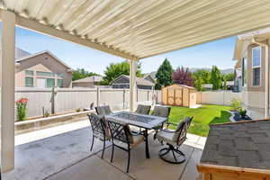 Fenced backyard with outdoor dining area, a patio, and a storage unit