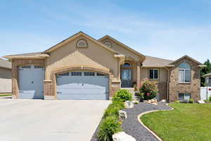 View of front of property with an attached garage, driveway, a front yard, and brick siding