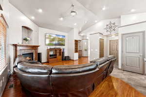 Living area with lofted ceiling, a fireplace, and a ceiling fan