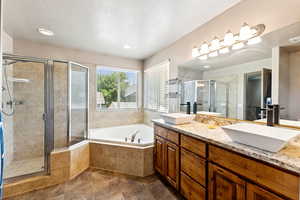 Bathroom featuring double vanity, a bath, a stall shower, tile patterned floors, and a textured ceiling