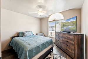 Bedroom with dark wood-type flooring, a ceiling fan, and a textured ceiling