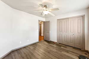 Unfurnished bedroom with wood finished floors, a closet, and ceiling fan