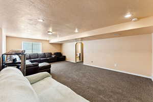 Carpeted living room featuring a textured ceiling and recessed lighting