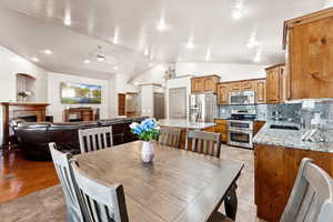 Dining area featuring vaulted ceiling, a tile fireplace, a ceiling fan, and light tile patterned floors