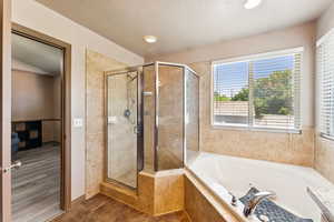 Bathroom with a whirlpool tub, a stall shower, tile patterned flooring, and a textured ceiling