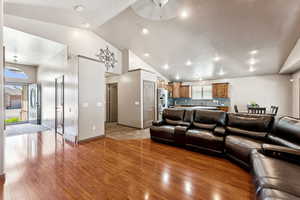 Living area with light wood-type flooring, ceiling fan, and high vaulted ceiling