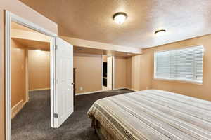 Bedroom with dark carpet and a textured ceiling