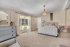 Bedroom featuring lofted ceiling, carpet flooring, access to exterior, and a textured ceiling