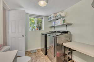 Laundry room with washer and clothes dryer and a textured ceiling
