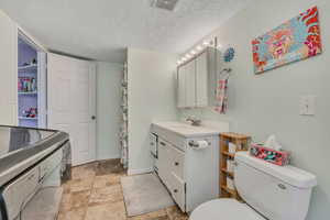 Bathroom with vanity, a textured ceiling, and curtained shower