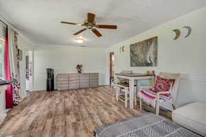 Sitting room featuring a textured ceiling, wood finished floors, a ceiling fan, and crown molding