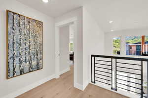 Corridor with wood finished floors, an upstairs landing, and recessed lighting