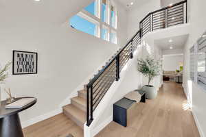 Stairs with a towering ceiling, wood finished floors, and recessed lighting