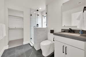 Bathroom featuring vanity, a spacious closet, and a shower stall