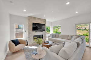 Living room featuring recessed lighting, a stone fireplace, and light wood-style floors