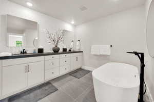 Bathroom with double vanity, a soaking tub, decorative backsplash, and recessed lighting