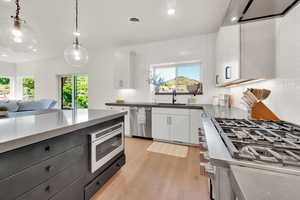 Kitchen featuring stainless steel appliances, backsplash, white cabinets, light wood-style flooring, and recessed lighting