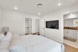 Bedroom with light wood-style floors, recessed lighting, a spacious closet, and ensuite bath