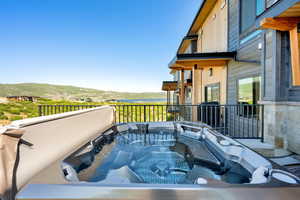 Patio / terrace with a hot tub and a water and mountain view