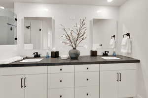 Full bath featuring backsplash, double vanity, and a shower stall
