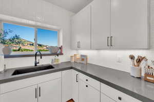 Kitchen with decorative backsplash, dark countertops, and white cabinets