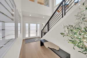 Foyer entrance with stairway, a high ceiling, light wood-style floors, and recessed lighting