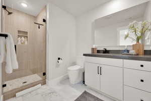 Bathroom featuring a shower stall, vanity, and marble finish floors