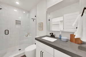 Bathroom with a shower stall, vanity, and recessed lighting