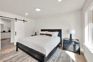Bedroom with a barn door, recessed lighting, and ensuite bathroom
