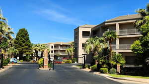 View of asphalt road with a gate, a gated entry, and curbs