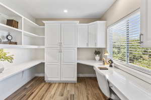 Office featuring built in desk, light wood finished floors, and recessed lighting