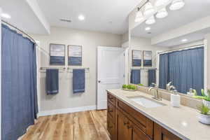 Bathroom with vanity, wood finished floors, a shower with shower curtain, and recessed lighting