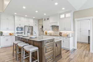 Kitchen featuring stainless steel appliances, a kitchen breakfast bar, recessed lighting, tasteful backsplash, and white cabinetry