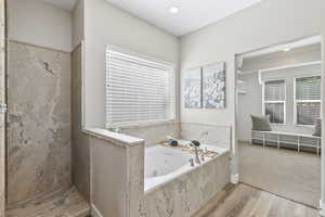 Bathroom featuring wood finished floors, a tub with jets, and a shower