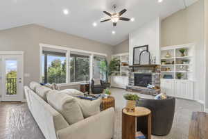 Living area featuring healthy amount of natural light, a fireplace, a ceiling fan, high vaulted ceiling, and recessed lighting