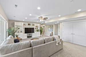 Basement living room with light carpet, recessed lighting, and ceiling fan