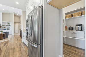 Kitchen featuring stainless steel appliances, white cabinets, light wood-style flooring, recessed lighting, and open floor plan