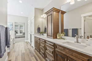 Bathroom with wood finished floors, double vanity, a tub, and recessed lighting