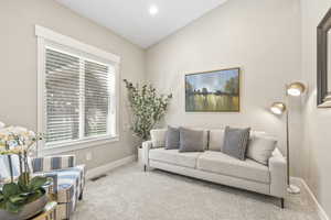 Living area featuring carpet floors and vaulted ceiling