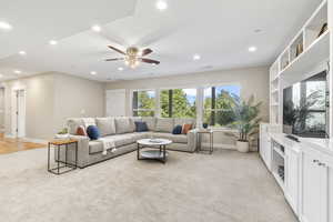 Basement living room featuring light colored carpet, recessed lighting, and a ceiling fan
