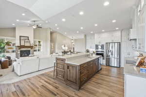 Kitchen featuring stainless steel appliances, white cabinetry, a ceiling fan, a spacious island, and light wood-style flooring