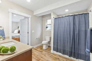 Full bathroom featuring vanity, wood finished floors, curtained shower, and recessed lighting